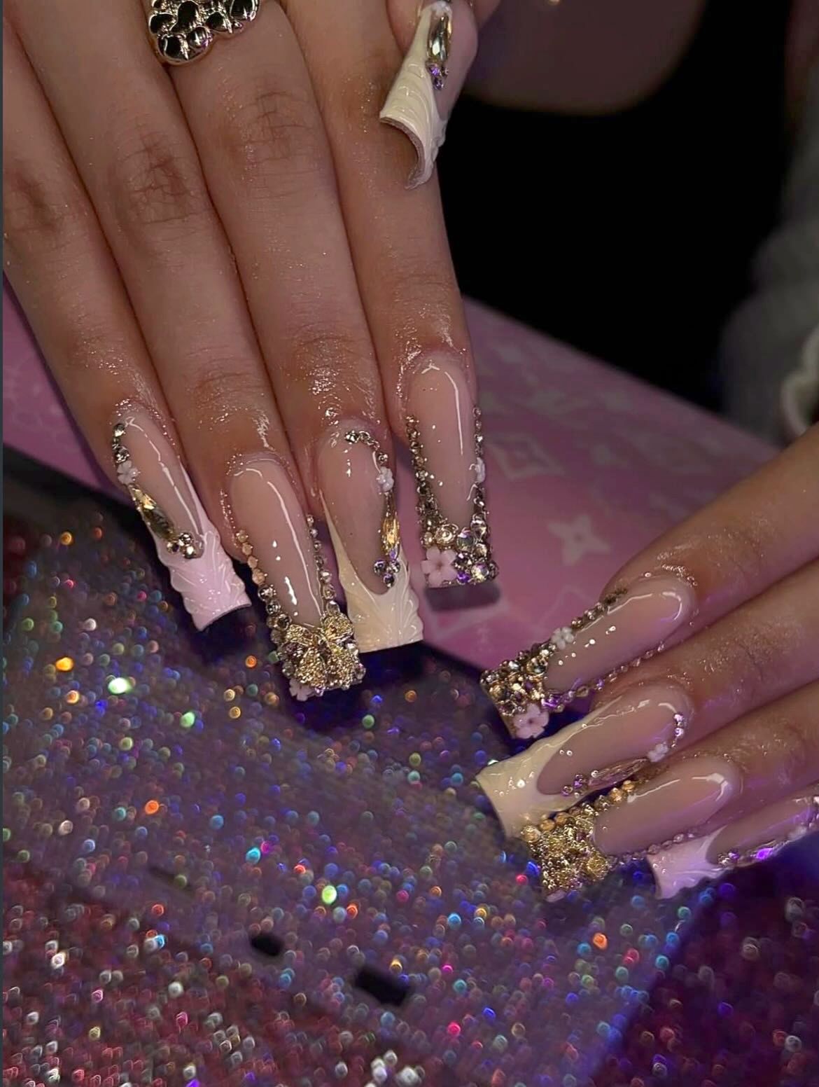 Long nude set with gold rhinestone charms over a glitter nail desk